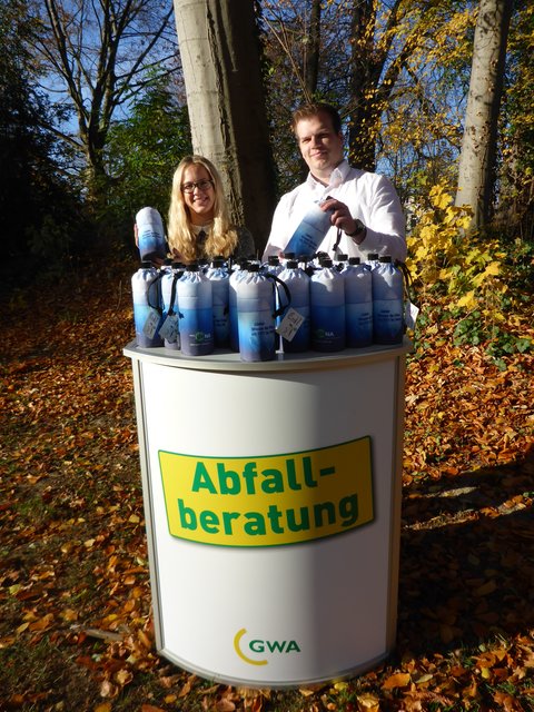 Die GWA-Auszubildenden Jasmin Kümper und Thorben Meyer präsentieren die Getränkeflaschen, die es zu gewinnen gibt.