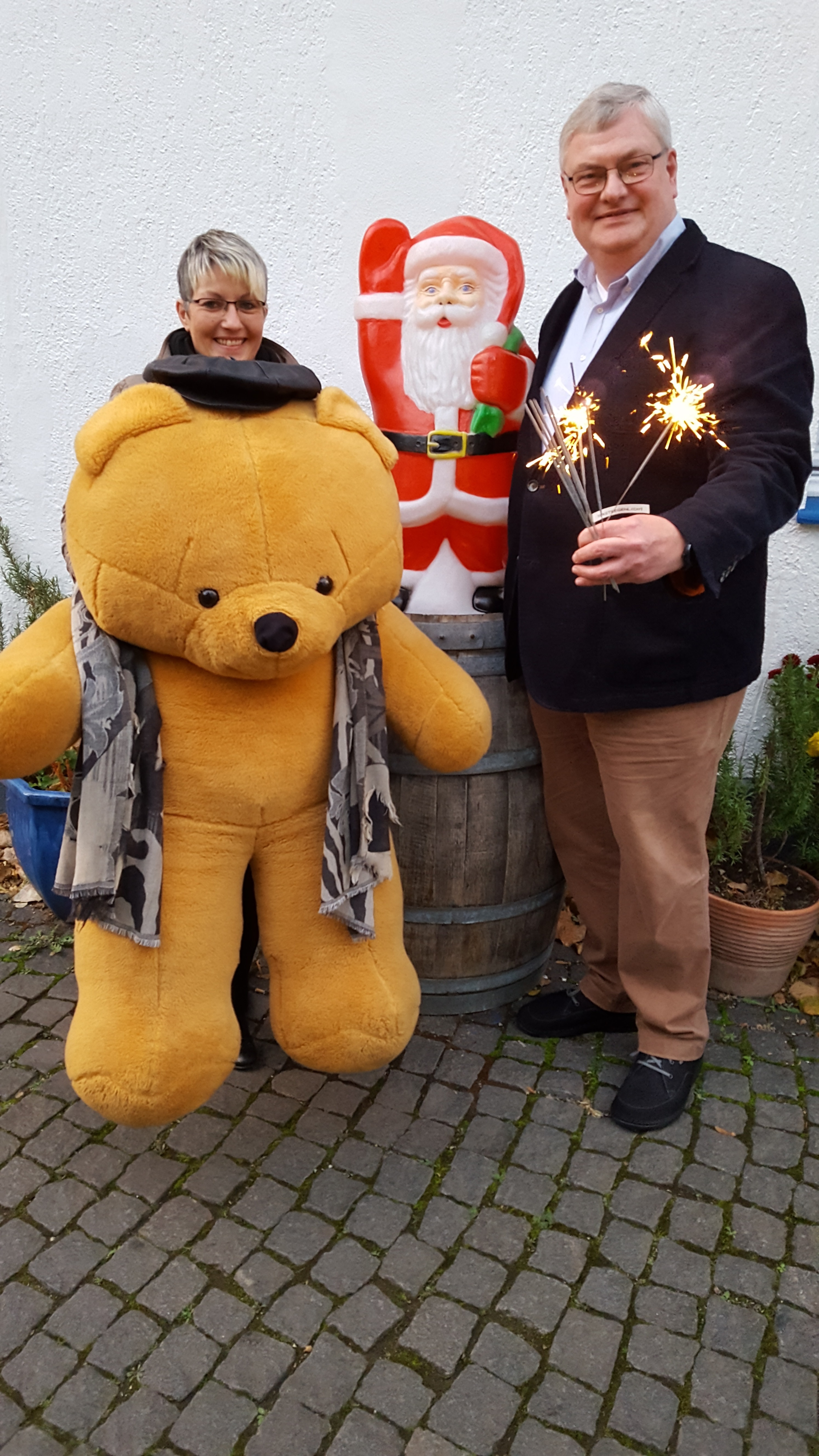 Dana Brettschneider und Markus Püll posieren mit dem größten Kuscheltier, das jemals für den Geschenkesack des Nikolauses gespendet worden ist und den Friedenslichtern, die nun Tersteegenlichter heißen.