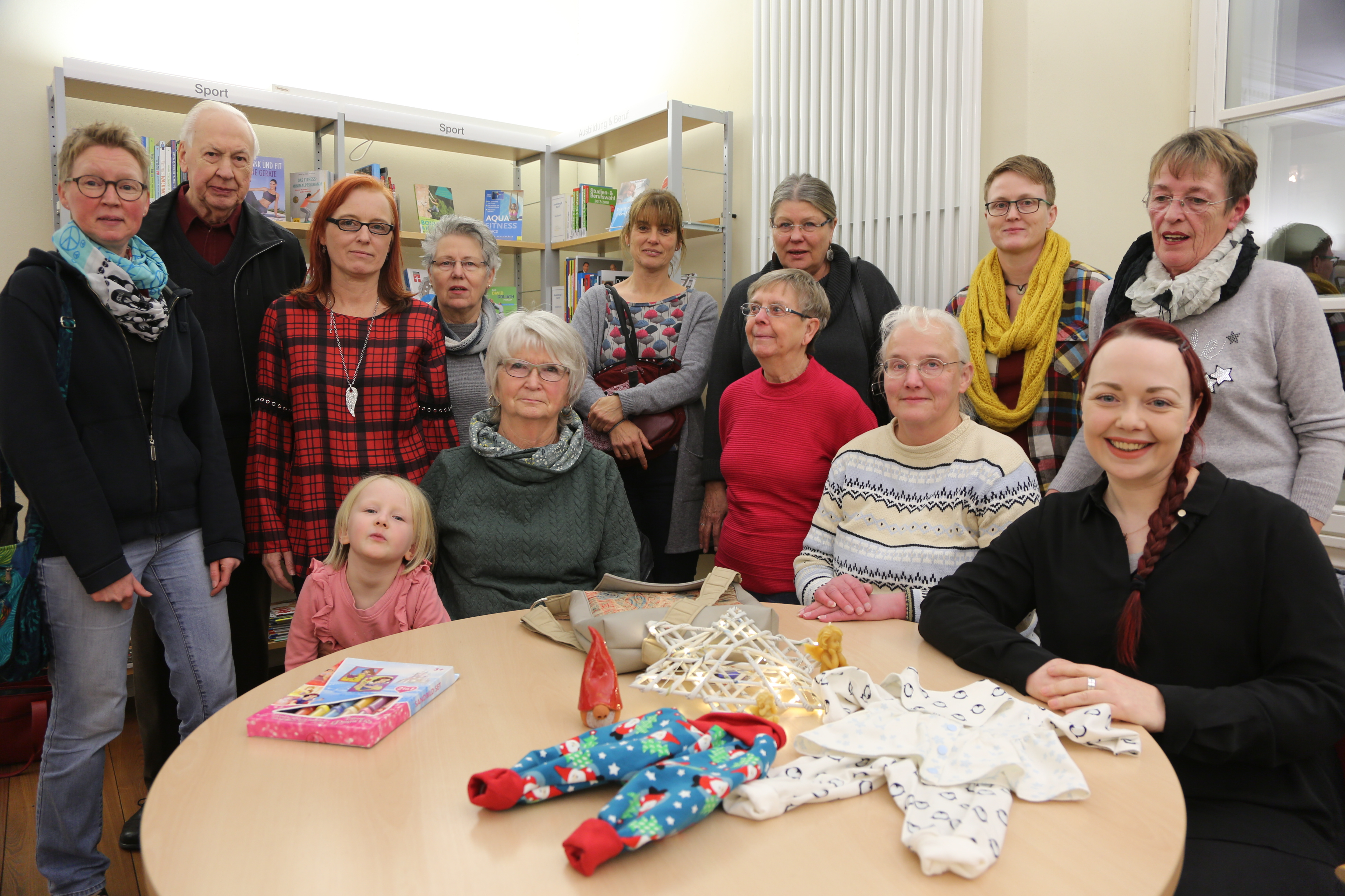 Stefanie Knippertz (sitzend rechts), Leiterin der Letmather Bücherei-Zweigstelle, freut sich über die rege Beteiligung von verschiedenen Gruppen und Anbietern anlässlich des Letmather Weihnachtsmarktes. Foto: Schulte