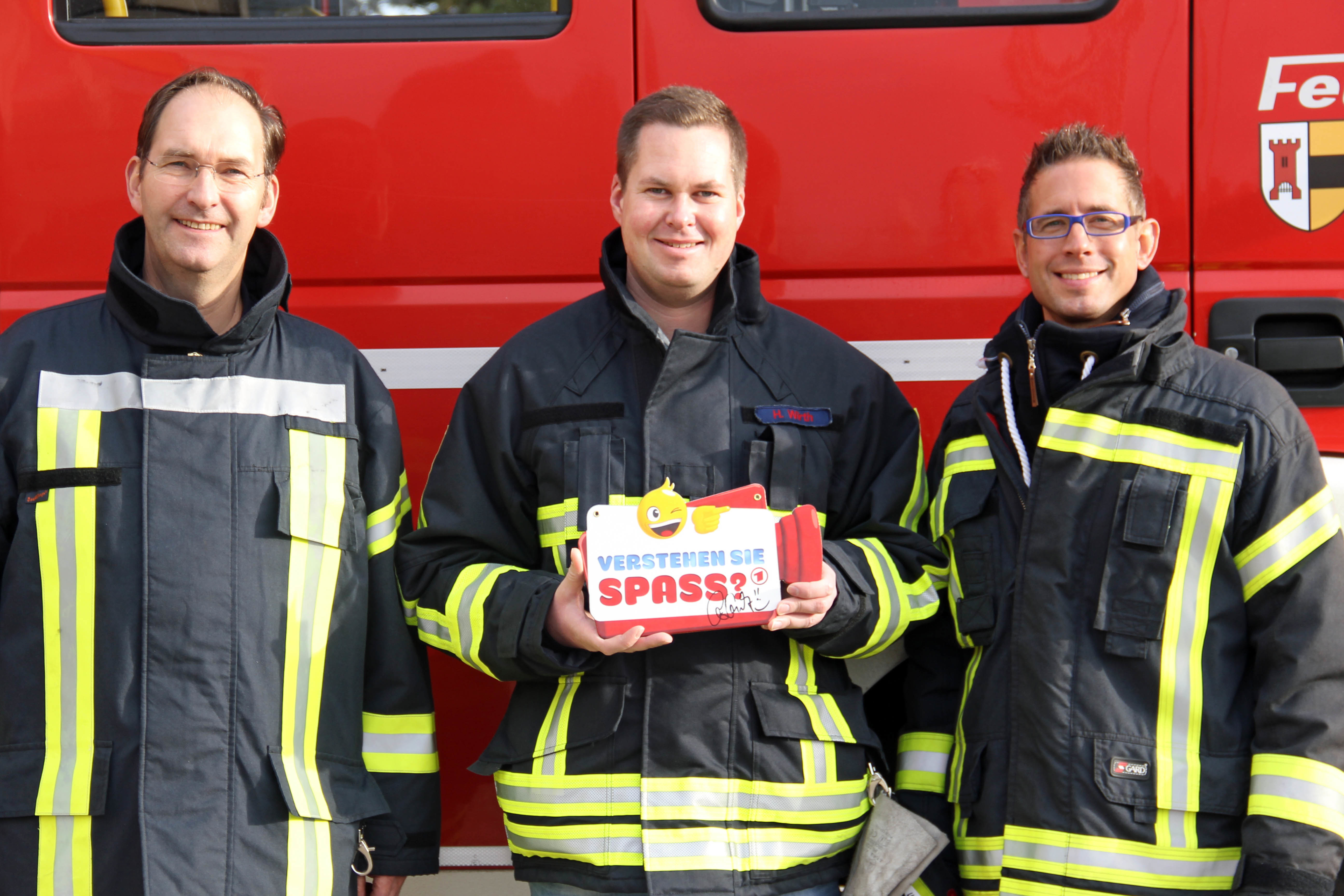 Hanno Wirth (Mitte) von der Feuerwehr Moers wurde Opfer eines Streichs bei „Verstehen Sie Spaß?“. Wehrführer Christoph Rudolph (l.) und Wachabteilungsleiter Christian Heekeren freuen sich über die geglückte Aktion.