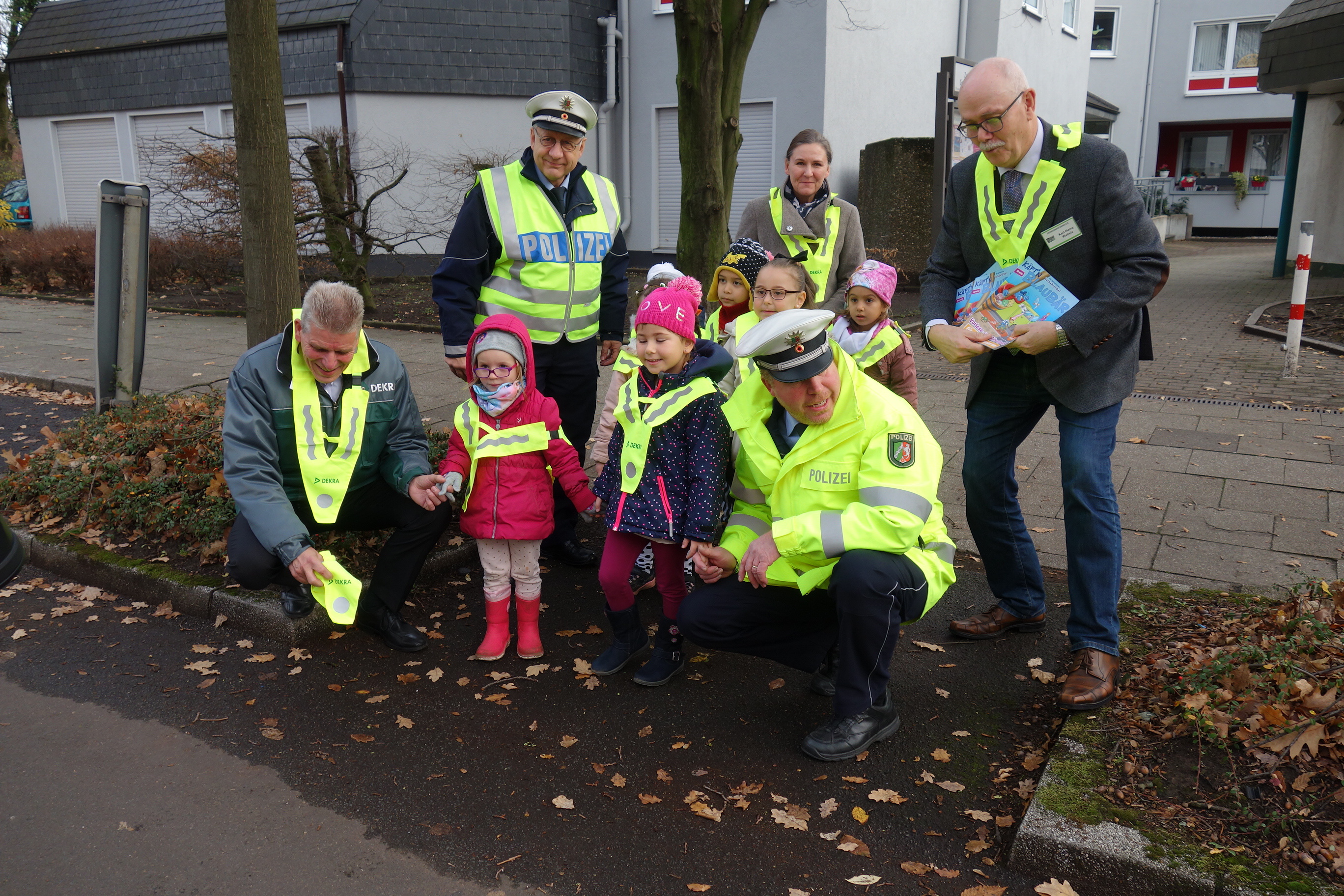 So süß, so gut sichtbar, gehen Kindergarten-Kleine über die Straße. Geschützt von li. Carsten Debler, Michael Hennig, Clauda Gerlach, Karl-Heinz Webels, vorne Georg Breidenbach.