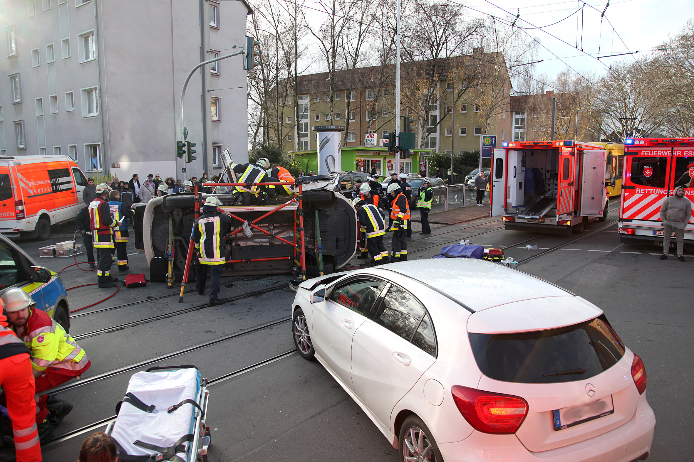 Das Taxi liegt auf der Fahrerseite, ist mit Streben stabilisiert. Die Einsatzkräfte haben sich eine Rettungsbühne aufgebaut, die ihnen den Zugang zum Fahrzeug erleichtert.