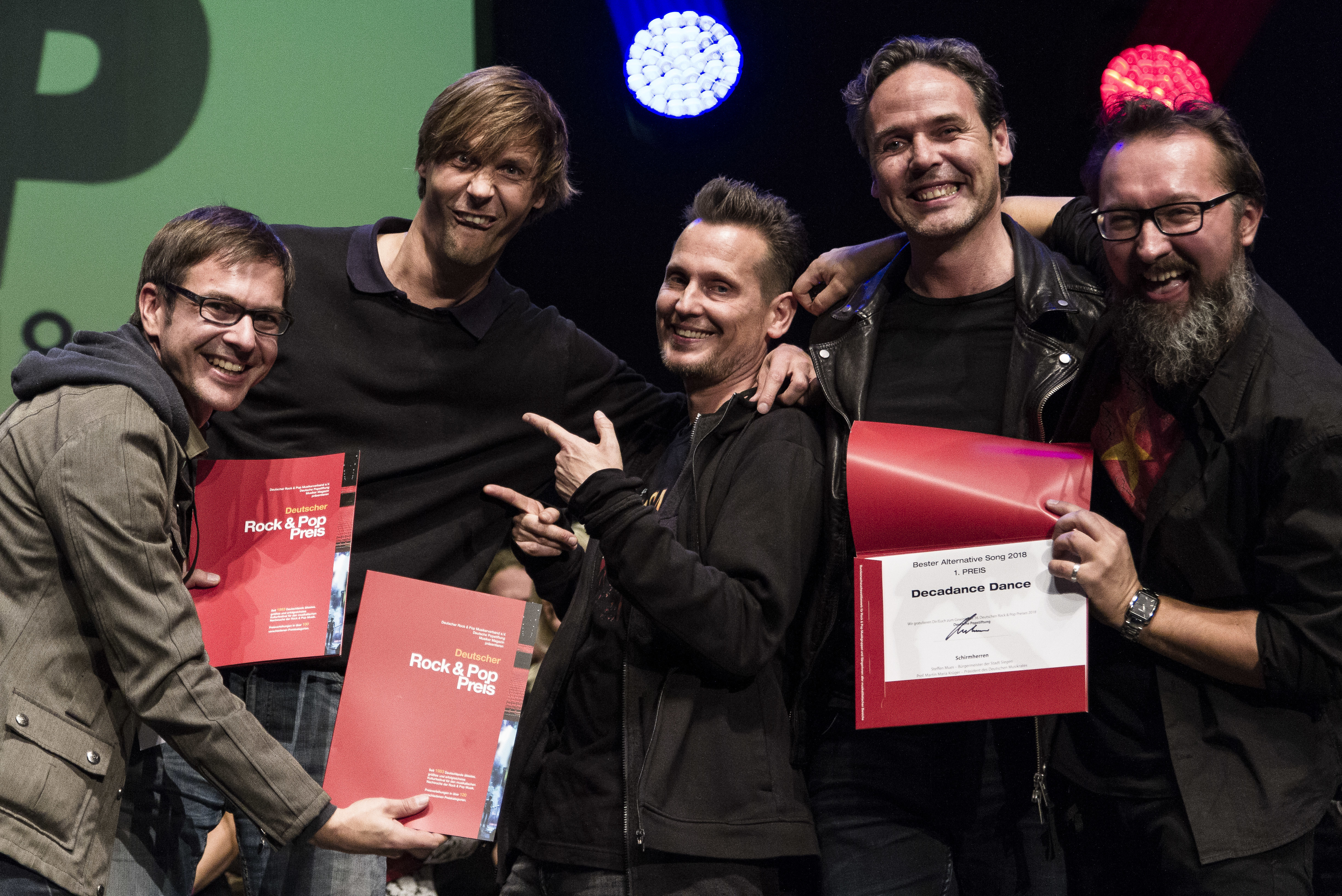 Bei der Preisverleihung in Siegen sind die Bandmitglieder ganz aus dem Häuschen(v. l.): Felix Meyer-Dietrich – guitars, Bosen Bosseler – drums, perc., Bordo Bortlisz – Vox, Frank van der Sant – guitars, Nogger Nogowski – bass. Nicht im Bild: Jensen Moeller – guitars, backing vox (+) und Herbie Kirchmeyer – drums.