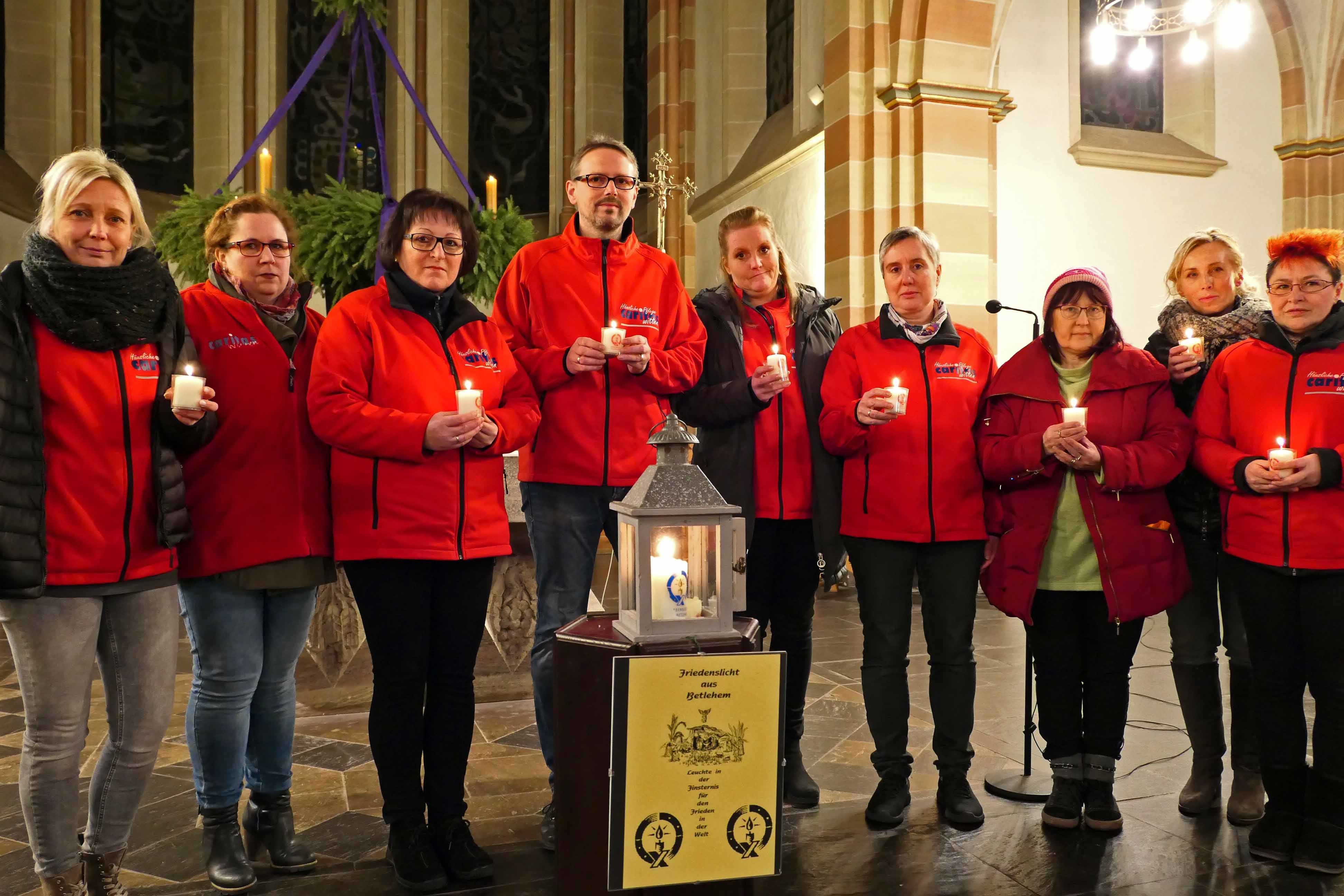 Caritas-Pflegekräfte verteilen Friedenslicht.