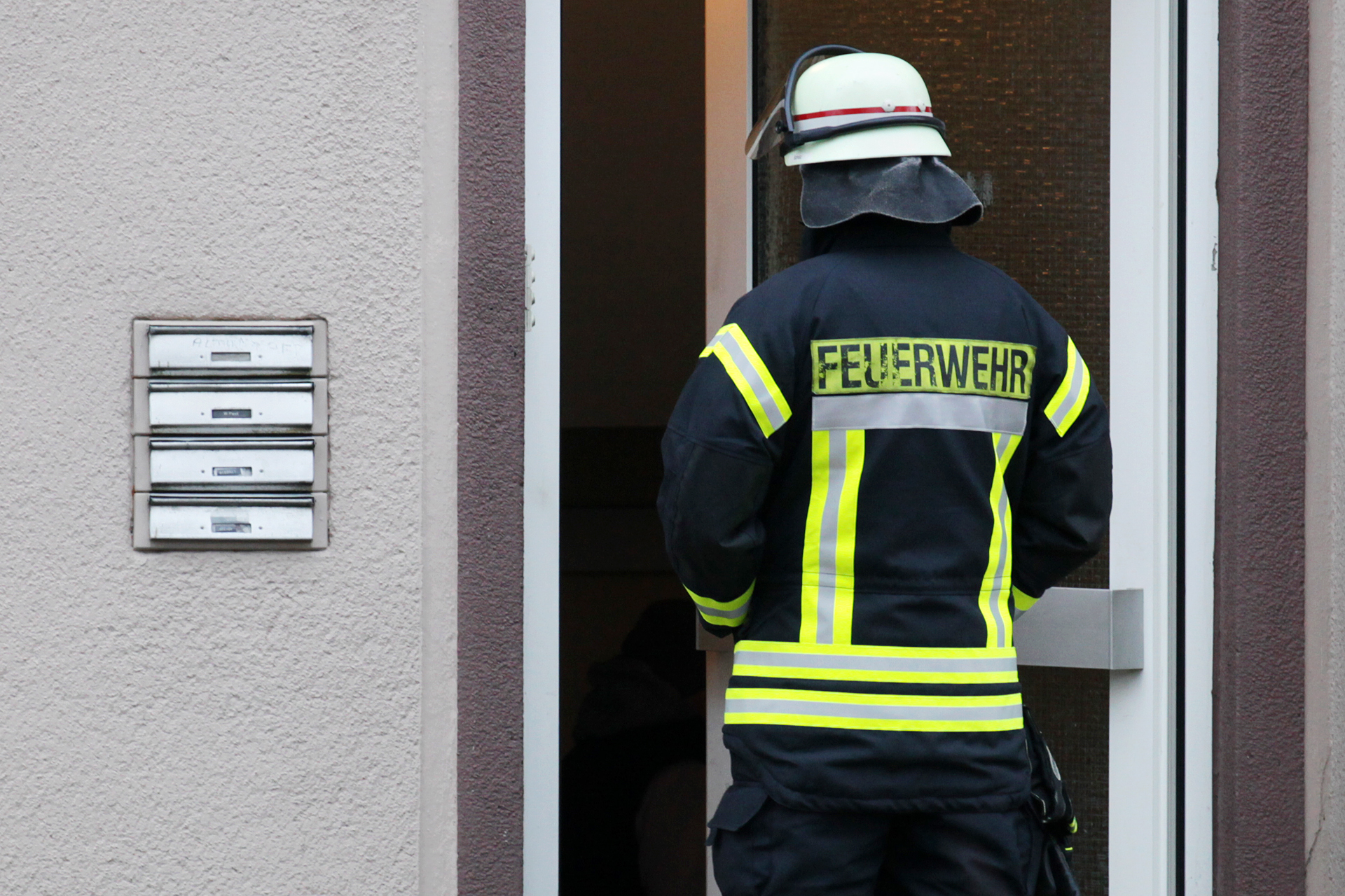 Ein Feuerwehrmann steht vor der Tür des Mehrfamilienhauses an der Gute-Hoffnung-Straße in Bergkamen-Oberaden.