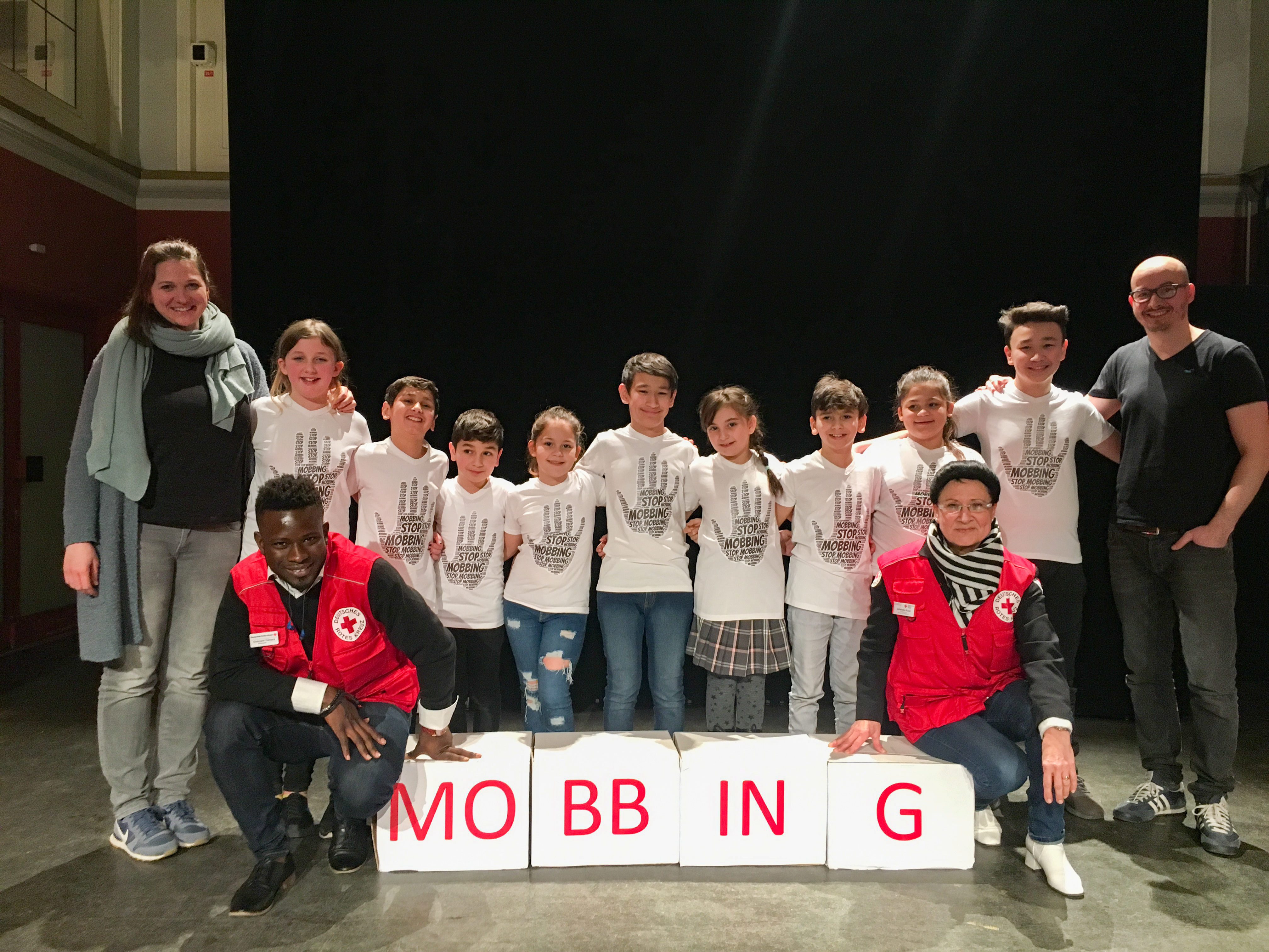 hinten v.l.: Janna Plate (Theaterpädagogin), Kinder der DRK-Theatergruppe "Die Sterne", Dirk Oskar Plate
vorne v.l.: Ousmare Camara (ehrenamtlicher Helfer im DRK), Jolanda Kuci (DRK- Projektleiterin Bildung und Integration)
