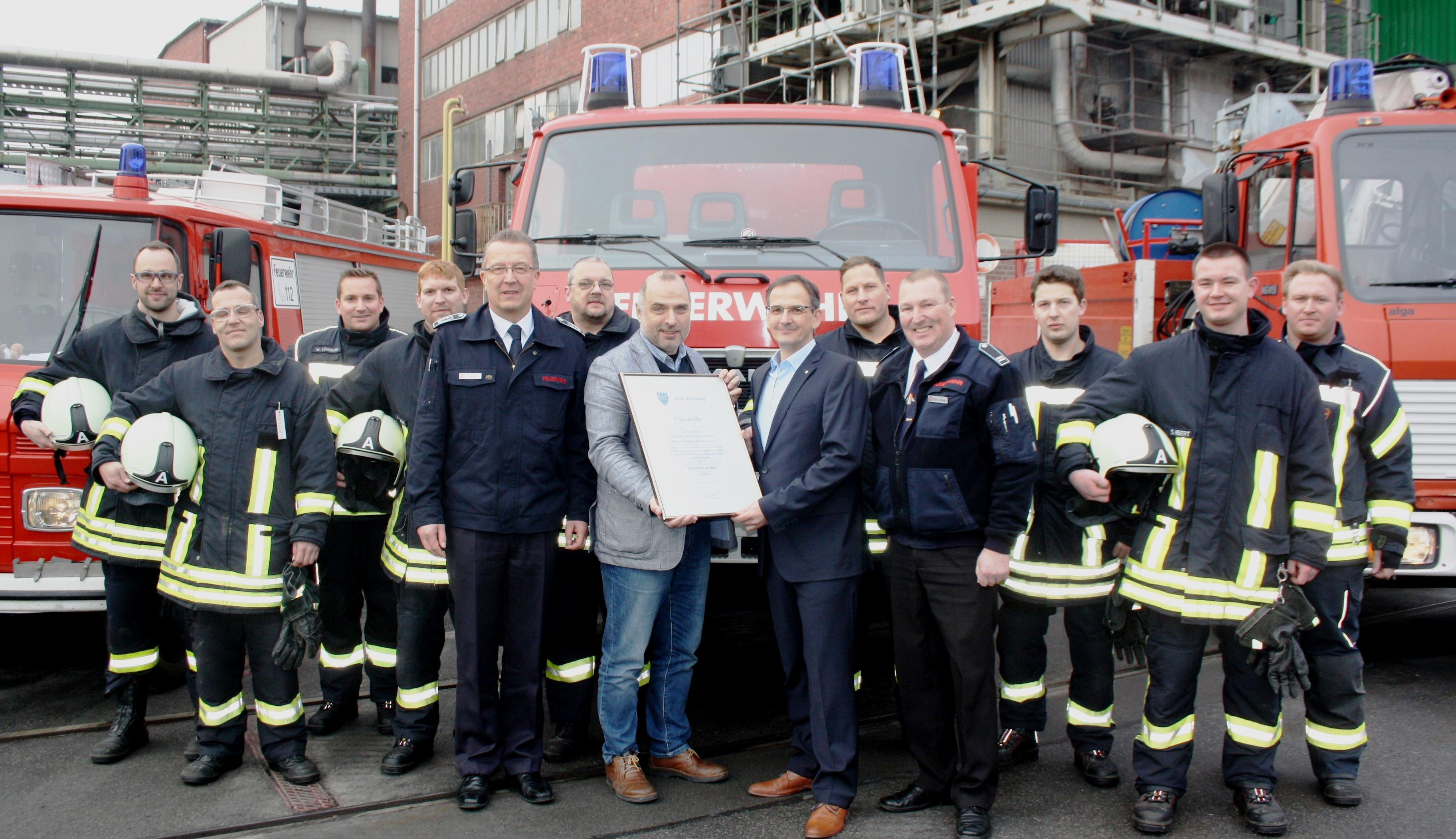 Bürgermeister Ralf Paul Bittner bei der Übergabe der Anerkennungsurkunde an Geschäftsführer Peter Hartmann, im Beisein des Leiters der Feuerwehr, Bernd Löhr, dem Leiter der Betriebsfeuerwehr, Dirk Sölken, sowie den Angehörigen der Betriebsfeuerwehr.