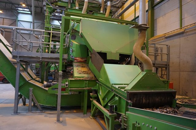 Altholz wird einer Zerkleinerungsmaschine zugeführt, damit in einem weiteren Schritt etwaige Kunststoff- oder Metallteile aussortiert werden können.