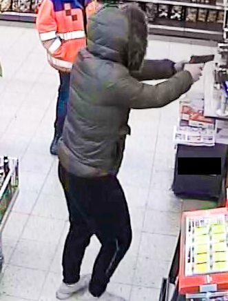 Der Dieb während des Überfalls. Klar zu sehen: die Waffe in seiner Hand.