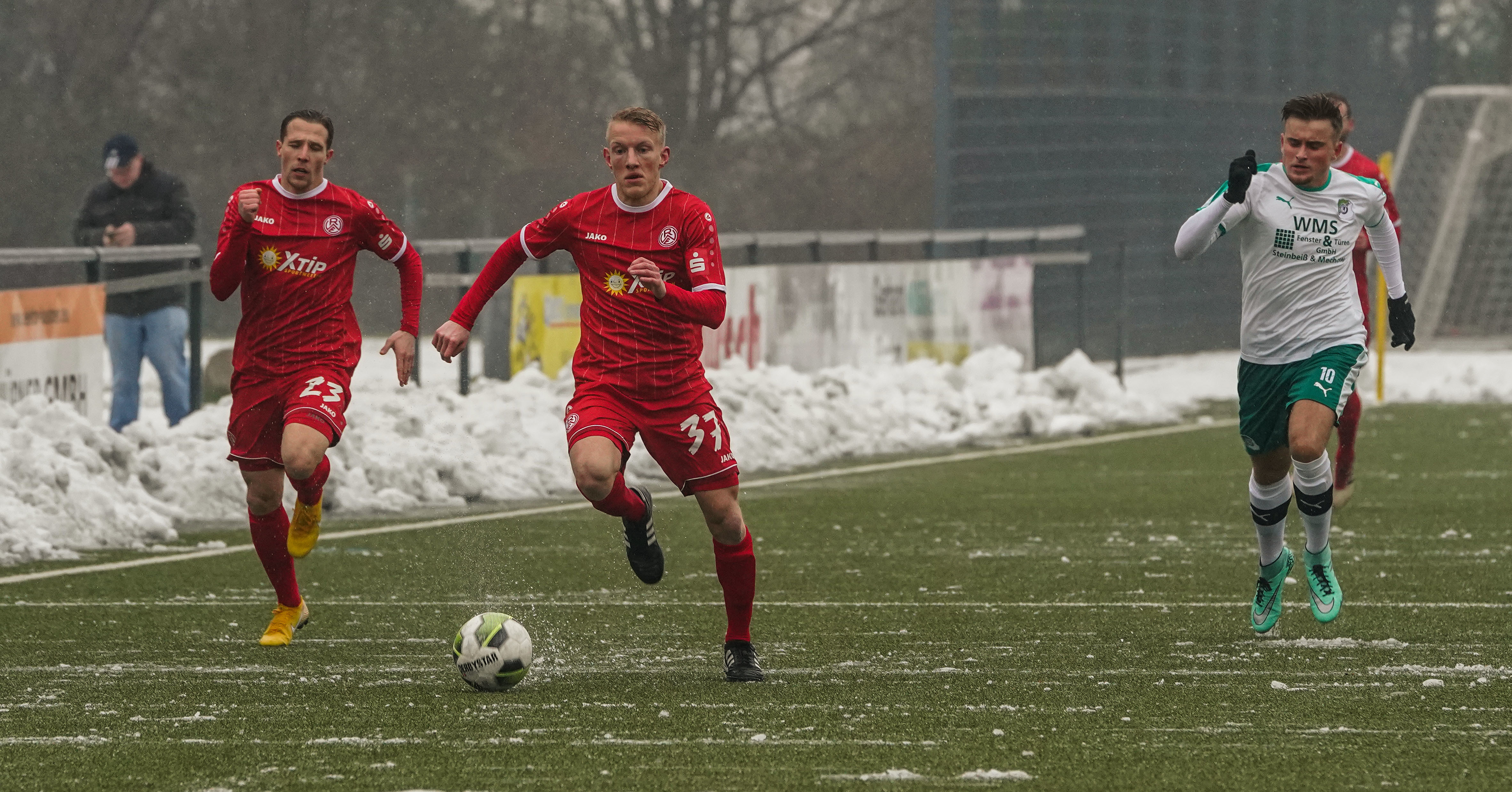Der vom Wuppertaler SV gekommene Jonas Erwig-Drüppel gab einen Vorgeschmack auf seine Schnelligkeit. Florian Bichler (l.) und Schonnebecks Luka Bosnjak (r.) versuchten an ihm dran zu bleiben. Am Spielfeldrand ist der Schnee zu sehen.