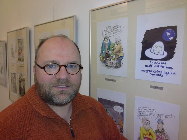 Jan Michaelis neben seiner Karikatur in der Mediengalerie in Berlin.