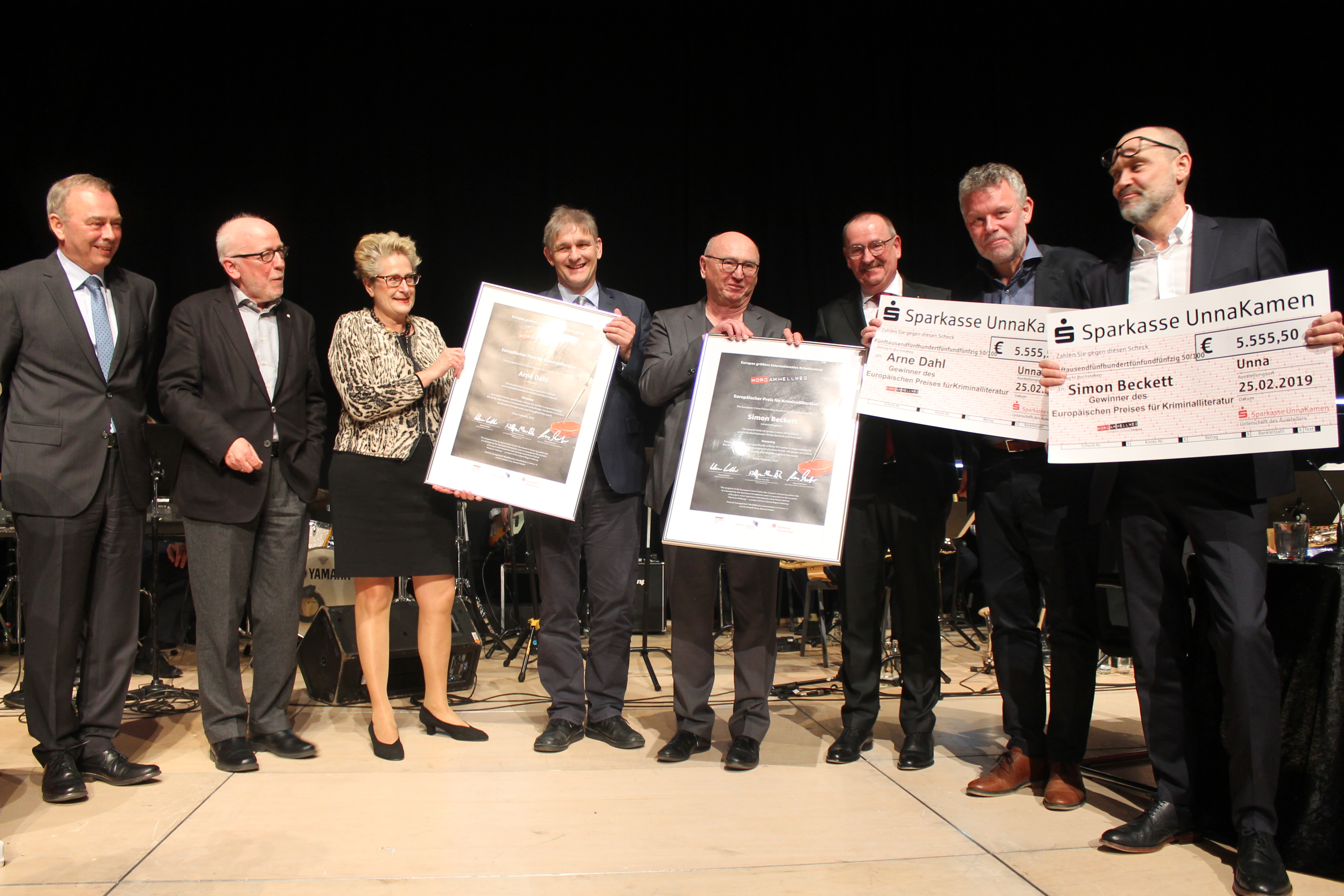 Werner Kolter (v.l.), Wolfram Kuschke, Sigrun Krauß, Michael Makiolla, Herbert Knorr und Klaus Moßmeier graturlieren Arne Dahl und Simon Beckett. Foto: Kreisstadt Unna