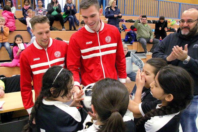 Die Rot-Weissen Florian Bichler (l.) und Boris Tomiak gratulieren dem Mädelsteam der Josefschule II mit einem signierten RWE-Ball.