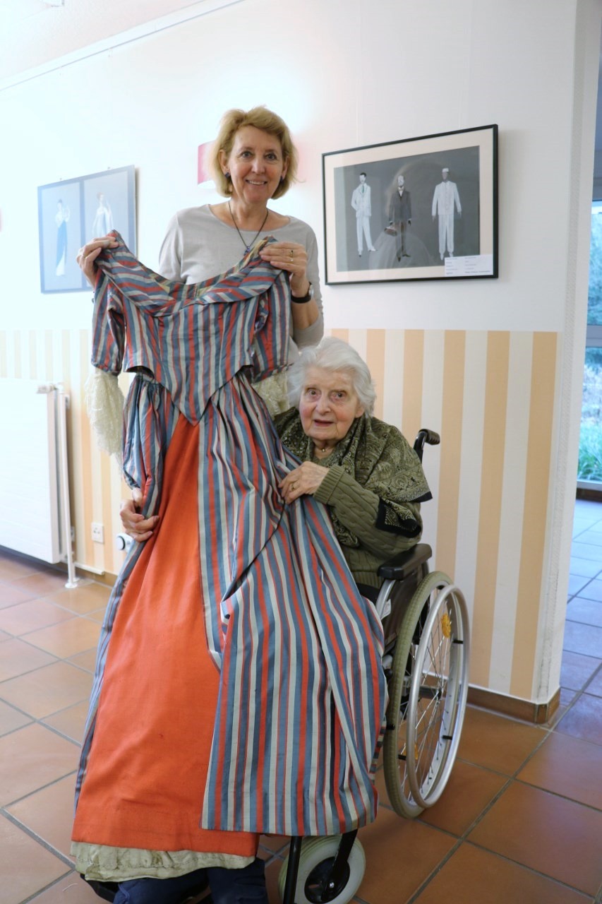 Edith Szewczuk (rechts) mit einem von ihr entworfenen Kleid aus einer Aufführung der Mozart-Oper „Così fan tutte“ in der Ausstellung des Gerricusstifts. Annelie Sturm (links) ist ihre nächste Verwandte und bewahrt einen großen Teil der vielen Zeichnungen, Fotos und Requisiten für Edith Szewczuk auf.