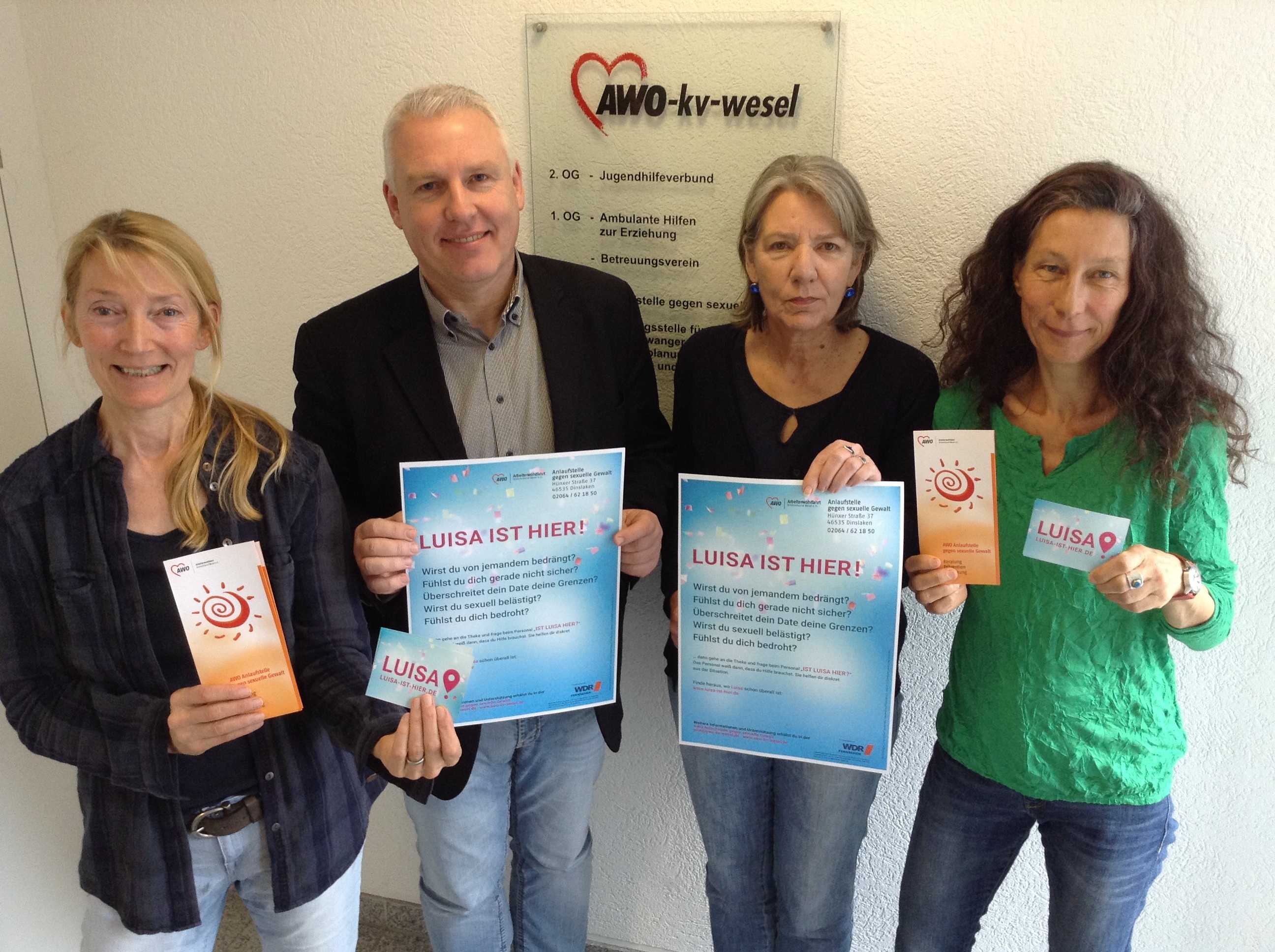 Das Plakat zur Kampagne "Luisa ist hier". V.l.: Stephanie Walbrunn (Einrichtungsleitung), Dr. Bernd Kwiatkowski (Geschäftsführer AWO Kreis Wesel), Antje Peter und Anja Krebs Mitarbeiterinnen der AWO-Anlaufstelle gegen sexuelle Gewalt Dinslaken.