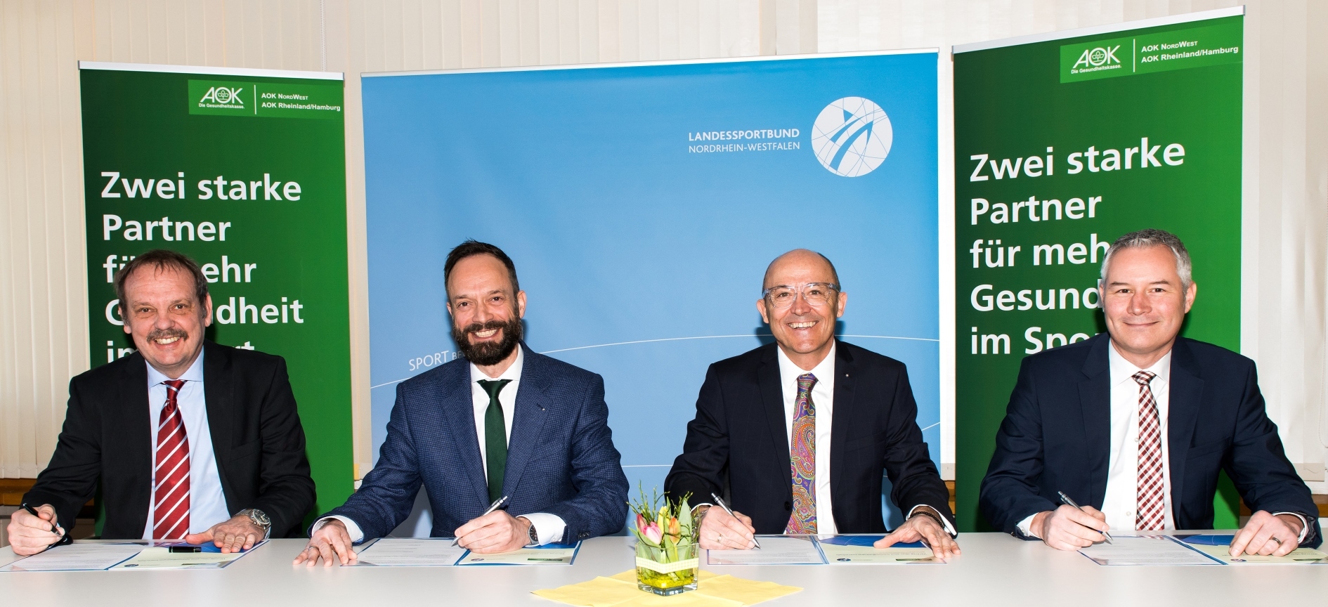 Ein gut gelauntes Quartett bei der Vertragsunterzeichnung, von links: LSB-Vorstand Martin Wonik, Tom Ackermann (Vorstandsvorsitzender AOK NORDWEST), Rolf Buchwitz (stellv. Vorstandsvorsitzender AOK Rheinland/Hamburg) und LSB-Vorstand Ilja Waßenhoven.