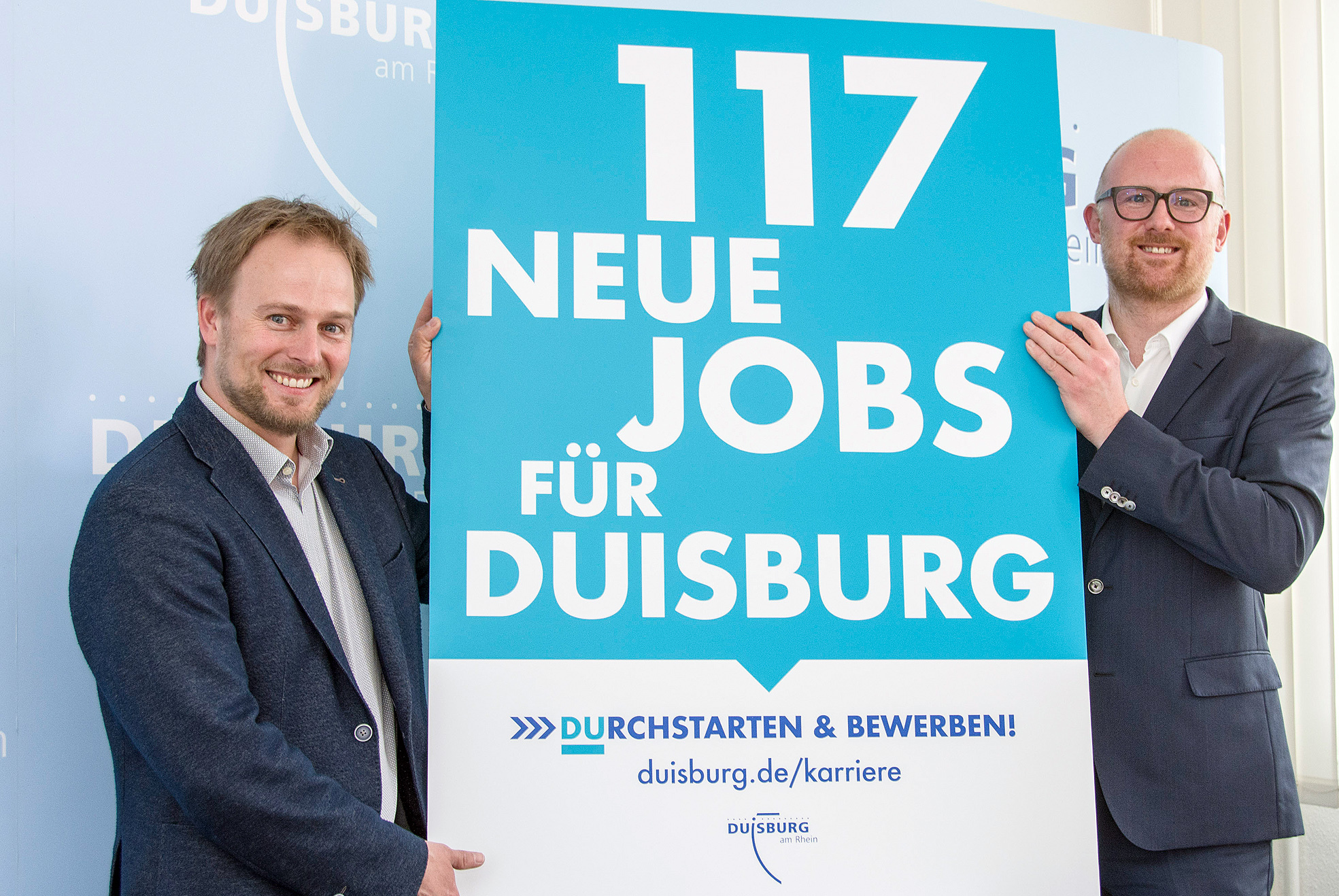 "Durchstarten und bewerben": Oberbürgermeister Sören Link (r.) und Stadtdirektor Martin Murrack (l.) präsentieren das Plakat zum Bewerbungsstart.