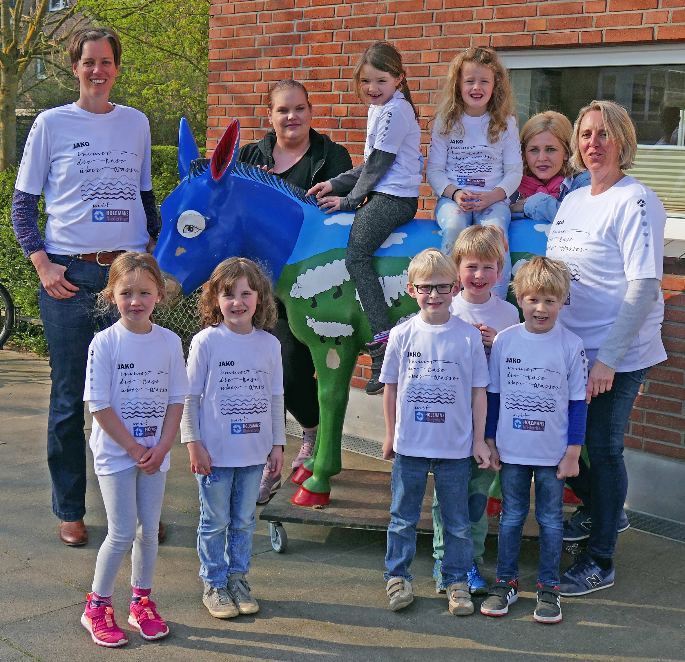 Holemans Niederrhein unterstützt das sportliche Engagement und spendierte den Kindern und ihren Betreuerinnen flott gestaltete T-Shirts mit dem Motto: „Immer die Nase über Wasser“.
Auf dem Foto: Marie, Schirin (auf dem Esel), Ria, Alina, Lukas, Sören und Titus mit ihren Betreuerinnen Katharina Flores, Cornelia Bückmann und Kita-Leiterin Sandra Gerdes (2. von rechts) sowie Holemans-Mitarbeiterin Beate Böckels (links).