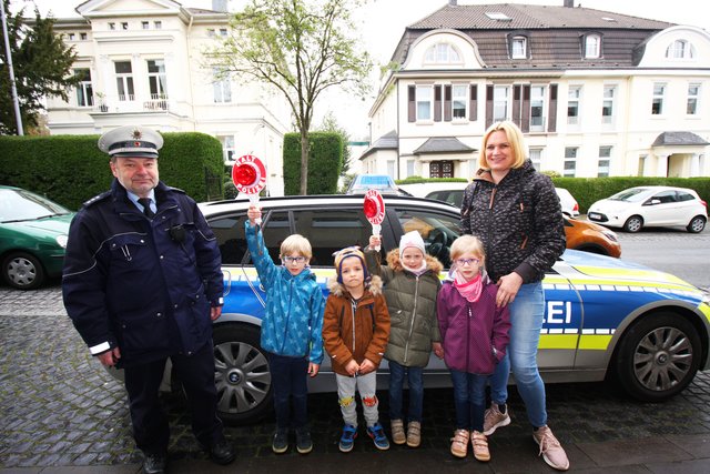 Polizeihauptkommissar Harald Schopp, Nadine Niederehe, Erzieherin im VKJ-Kinderhaus Am Wasser, und die KiTa-Kids an der Kettwiger Polizeiwache, wo sie nach dem Verkehrstraining exklusive Einblicke erhielten