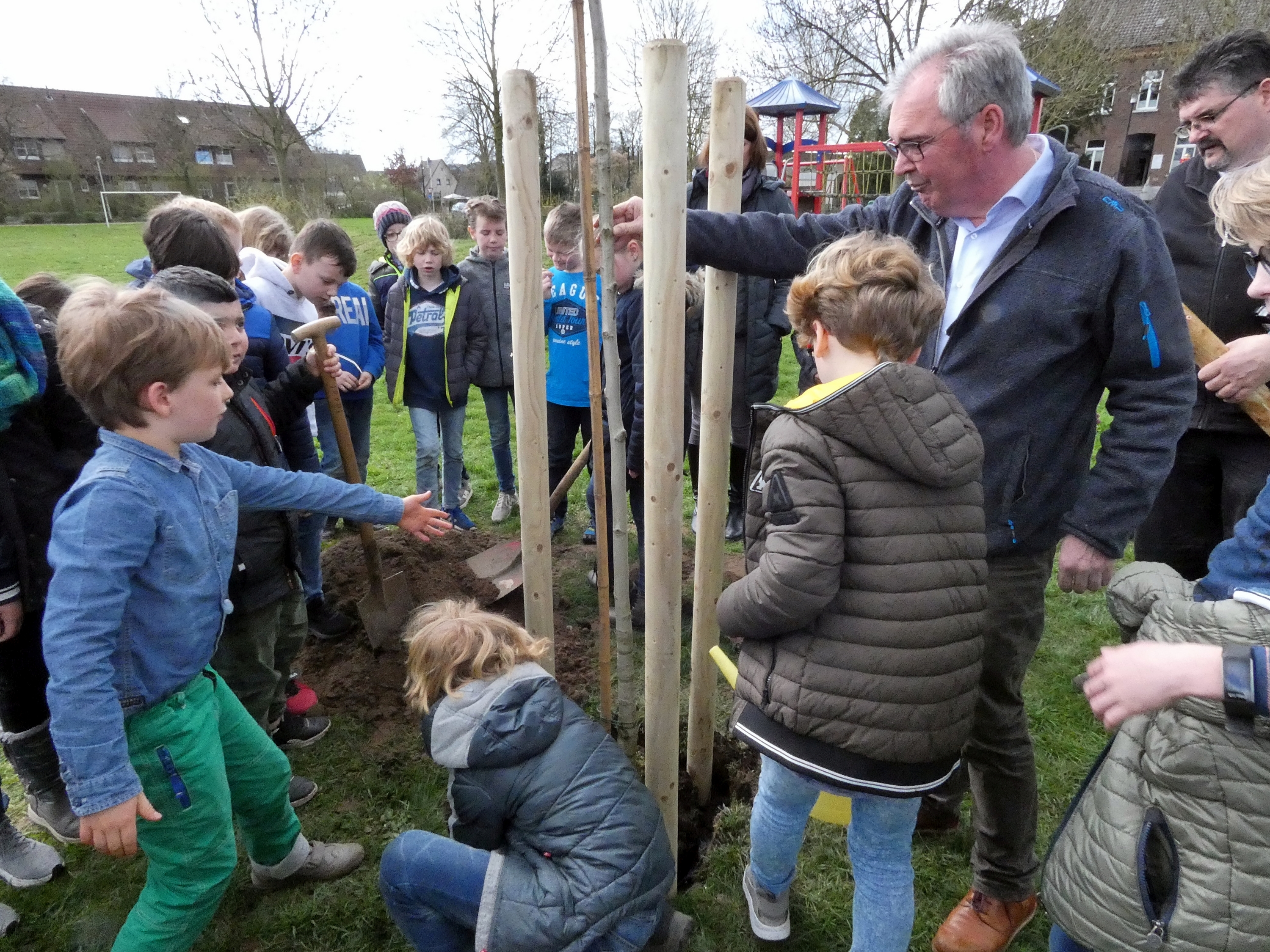 Das Foto zeigt Schulkinder der 4. Klassen, Klassenlehrerin Nathalie Wilden, Hausmeister Peter Winands und ARENACUM-Vorsitzender Josef Gietemann bei der jüngsten Pflanzaktion