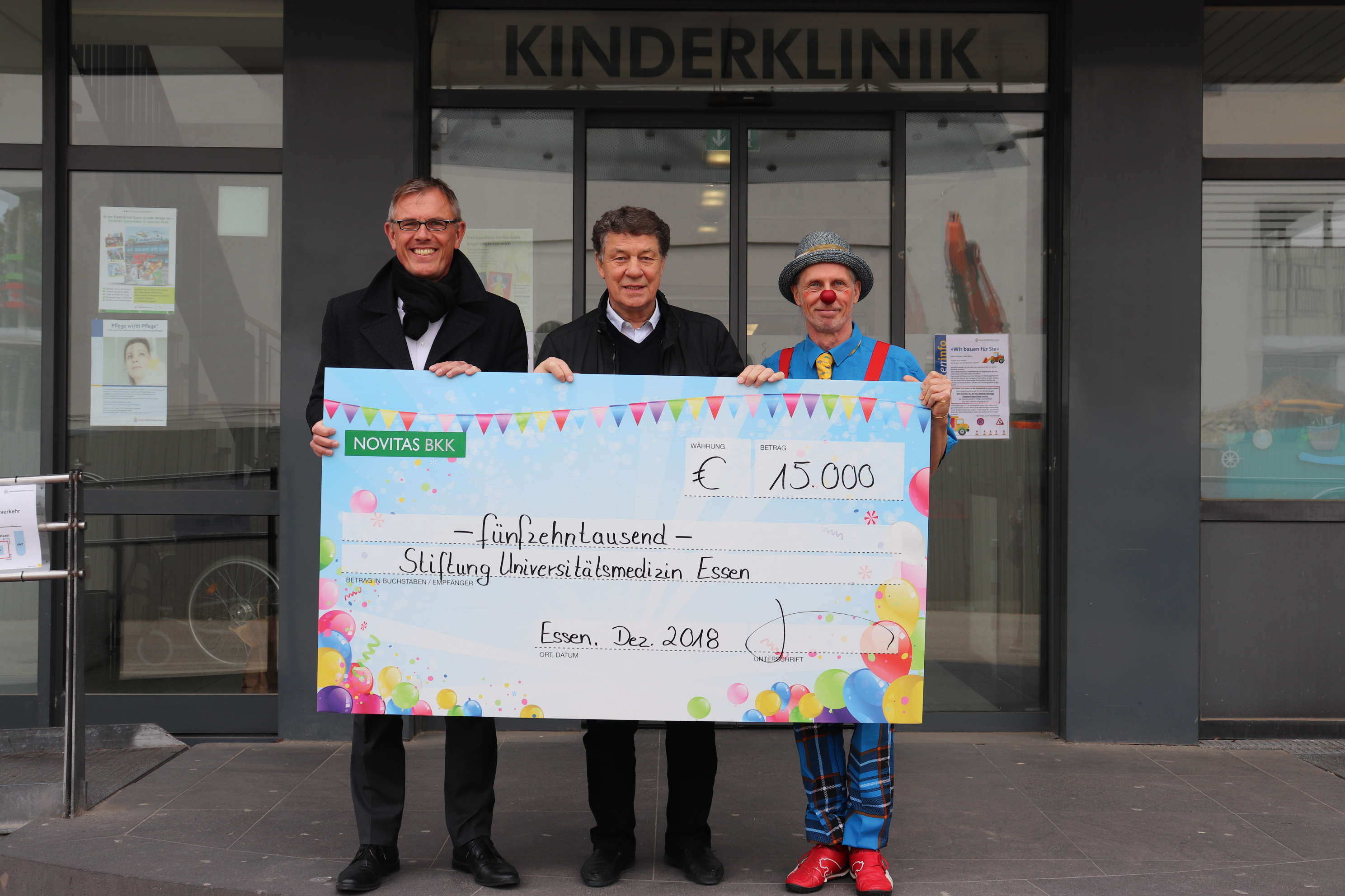 Frank Brüggemann, Vorstandsvorsitzender Novitas BKK, Otto Rehhagel, Kuratoriumsmitglied Stiftung Universitätsmedizin Essen, und Klinikclown Schlatke (v.l.) schauen der Zusammenarbeit weiterhin freudig entgegen.
