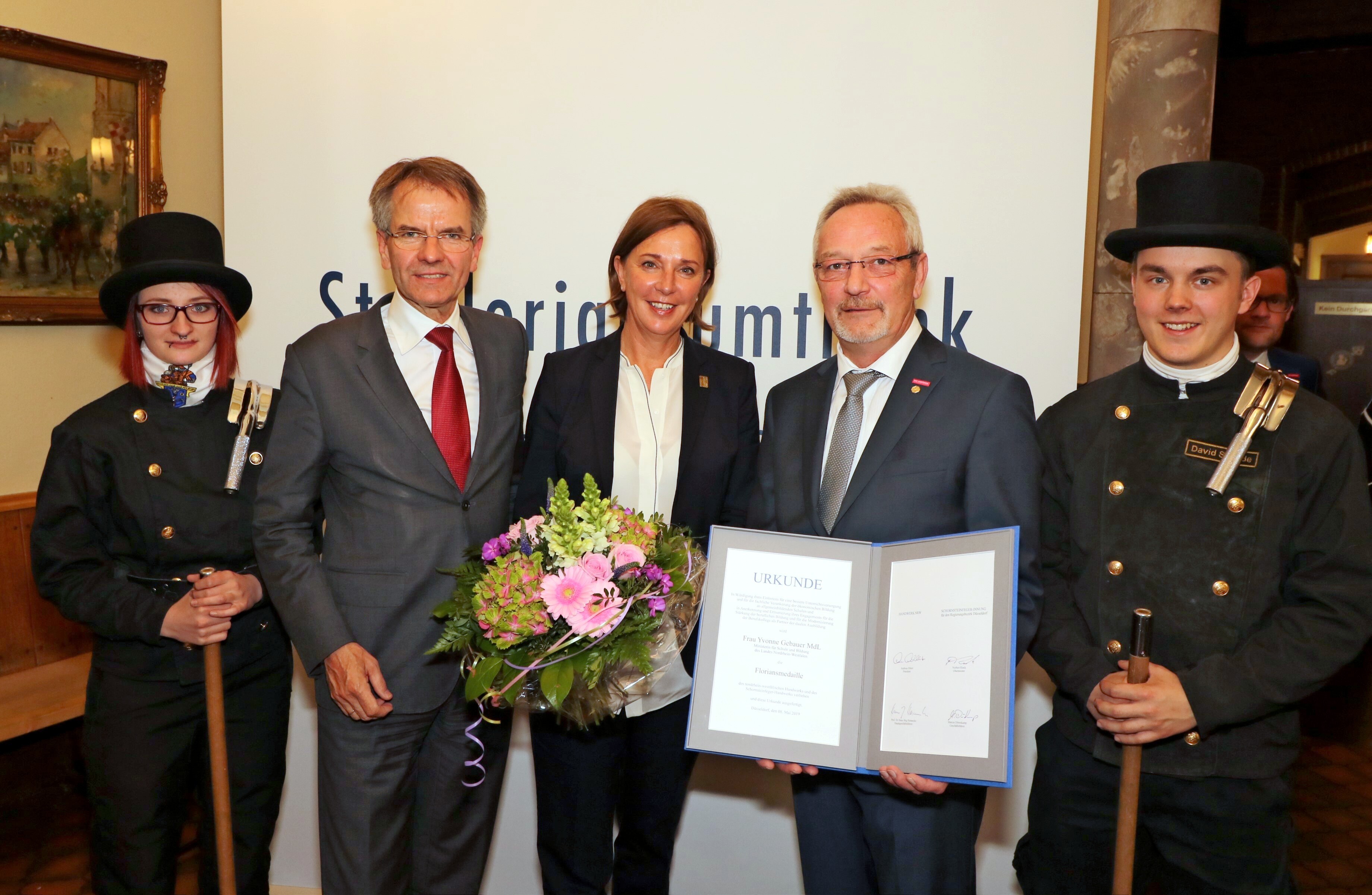 Schornsteinfeger-Obermeister Norbert Rieck (v.l.), Ministerin Yvonne Gebauer, NRW-Handwerkspräsident Andreas Ehlert und zwei Glücksbringer