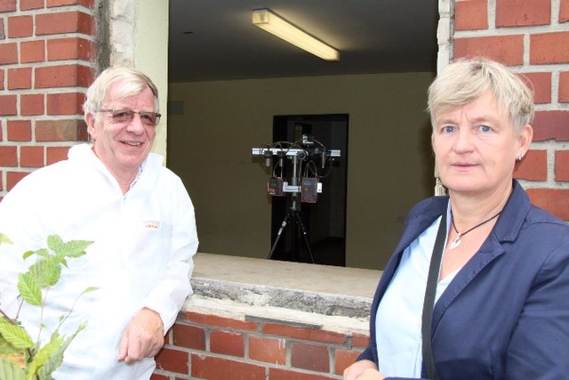 Hermann Fimpeler baut die Fenster fachgerecht unter Schutz aus, Baudezernentin Dr. Andrea Rüdiger erläutert die weiteren Arbeiten in den Schulen. Foto: Stadt