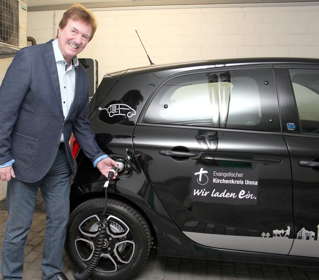 Superintendent Hans-Martin Böcker schließt das neue E-Auto an die Ladestation im Haus der Kirche.