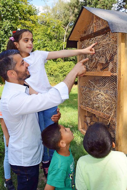 Vater Essam Alkuwaifi und Tochter Farah präsentieren mit Unterstützung von Abdullah und Ghazi (v.l.n.r.) stolz eines der beiden jetzt "neu eröffneten" Insektenhotels auf der Wildblumenwiese auf dem Dortmunder Hauptfriedhof.