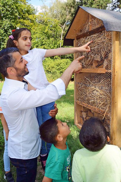 Vater Essam Alkuwaifi und Tochter Farah präsentieren mit Unterstützung von Abdullah und Ghazi (v.l.n.r.) stolz eines der beiden jetzt "neu eröffneten" Insektenhotels auf der Wildblumenwiese auf dem Dortmunder Hauptfriedhof. | Foto: Günter Schmitz