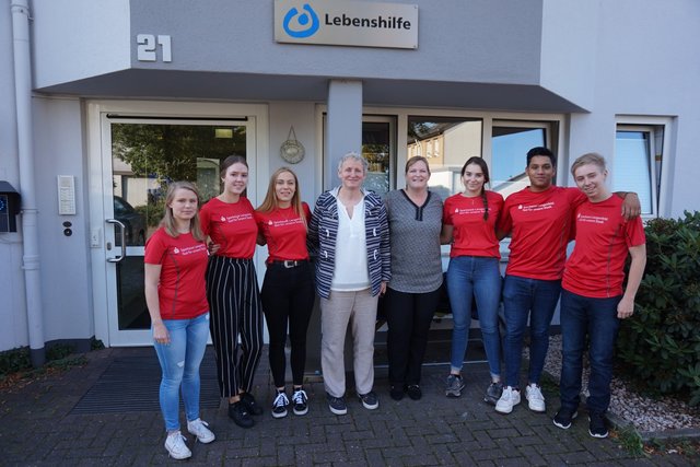 Begrüßung vor dem Lebenshilfe-Wohnheim:
Laura Wischmeier, Nina Szauer, Anita Frescher, Marion Maxfield (Leiterin des Wohnverbundes), Daniela Bogan (Verantwortlich für die Auszubildenden der Sparkasse), Johanna Küpper, Luciano Uguccioni und Jonas Terbrüggen v.l.n.r.