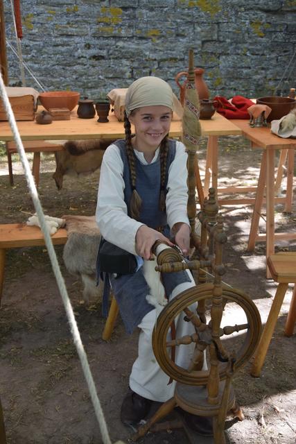 Die elfjährige Berenike verarbeitet am Spinnrad Schafswolle zu Garn.