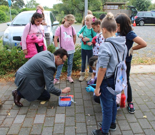 Schüler malen mit dem Bürgermeister symbolische Fußabdrücke in der Haltezone