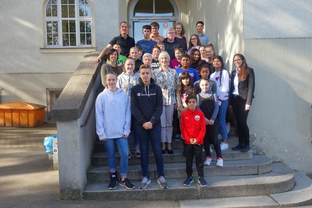 Strahlende Schulleiterin Rita Williams (mittig), hat dringende Wünsche; hier mit Lehrerinnen Susanne El-Faramawy (re.) Janneke Mette (li.) Lehrer Christian Schubert, oben (li.) Schüler-/innen der Klassen 5, 8, 10.