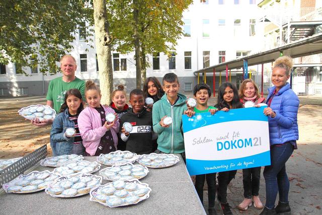 Zum gemeinsamen Abschlussfrühstück der Projektwoche spendierte DOKOM21 seinen Patenkindern speziell für sie gebackene „Amerikaner“. Helen Waltener (r.), Marketing-Mitarbeiterin von DOKOM21, und Klassenlehrer Imo Gatz (l.) verteilten das Gebäck an die begeisterten Schüler der Jahrgangsstufe fünf.