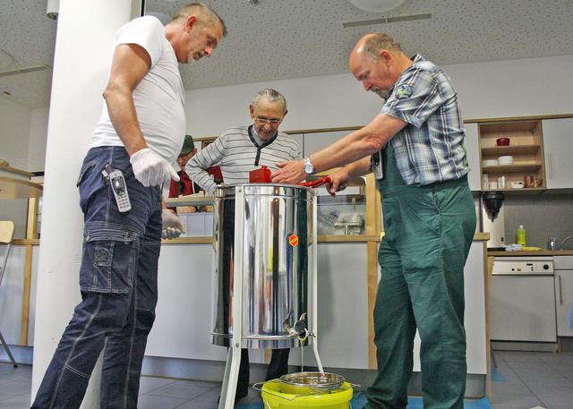 Klaus Raschke, Manfred und Frank Rennecke (v.l.) von der Bienen-AG der Wilfried-Rasch-Klinik freuen sich, als der erste selbst geerntete Honig aus der Schleudertrommel fließt.