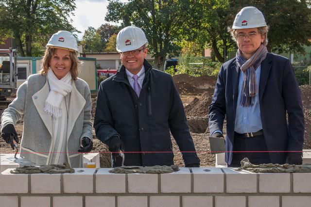 Christa Jahnke-Horstmann, Leierin des Vorstandsbereichs 2, Bürgermeister Dr. Michgael Heidinger und Dr. Thomas Palotz, Leiter Vorstandsbereich 3 üben sich im Erstellen einer Mauer, allerdings für den guten Zweck