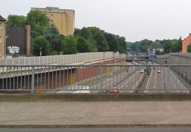 Hier an der Steeler Strasse, unter der Strassenbahnhaltestelle "Schwanenbusch" verschwindet die A52 seit Jahrzehnten auf vielen Hundert Metern unter einem begrünten, wie auch begehbaren Autobahndeckel - für die Lebensqualität in Huttrop ein nicht unerhebliches Bauwerk. So etwas was endlich auch für Frohnhausen/Holsterhausen möglich sein.
