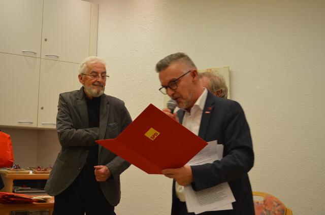 Der SPD-OB-Kandidat Oliver Kern überreicht für 60 Jahre Parteitreue Prof. Dr. Rainer Ansorg die Urkunde und liest aus dem Urkundentext vor. Auf die Frage, wie seine Umgebung auf seinen Eintritt in die SPD reagierte, antwortete er: „Geh doch nach drüben!“