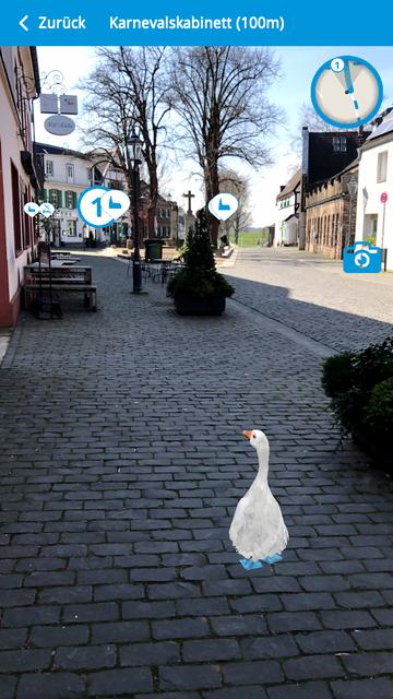 Wenn ein Ziel ausgewählt wurde, wird die App zur sogenannten Augmented-Reality-Anwendung: Direkt vor den eigenen Füßen watschelt die Gans zum Karnevalskabinett.
Foto: Screenshot/Stadt Monheim am Rhein