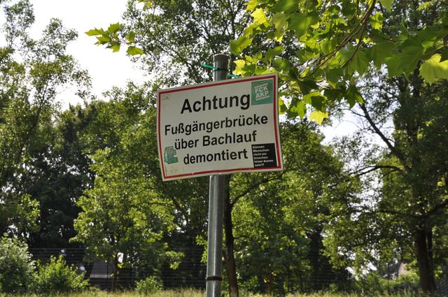 Das Warnschild, das auf die Demontage der ehemals vorhandenen Fußgängerbrücke hinweist, zeigt in die falsche Richtung.  | Foto: cHER
