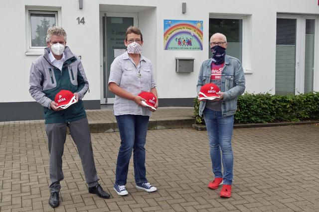 Dekra-Niederlassungsleiter Carsten Debler (links) überreichte gemeinsam mit Bürgermeister Fred Toplak (rechts) signalrote Sicherheitskappen an Simone Wallbaum (Mitte), Leiterin des katholischen Kindergartens St. Ludgerus. Foto: ST