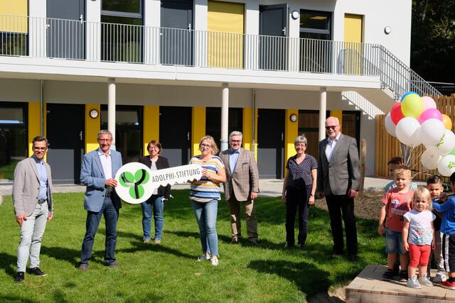 Symbolische Schlüsselübergabe Grevel-KiTA: Architekt Peter Lammsfuß, Adolphi-Geschäftsführer Dirk Gersie, Presbyteriums-Vorsitzende Monika Fränkel, Dunja Klaus, stellvertretende Kita-Leiterin, Geschäftsbereichsleiter Ulrich Leggereit, Pfarrerin Susanne Gutjahr-Maurer und Geschäftsführer Joachim Eumann (von links) freuen sich gemeinsam mit den Kita-Kindern über die Fertigstellung des Neubaus.