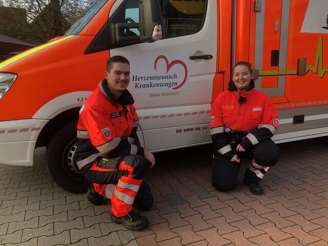 Rettungshelferin Sofie Gerdes und Rettungssanitäter Matthias Kemper mit dem Logo für die Herzenswunsch-Krankenwagen.