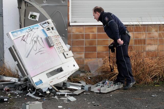 Ein Polizist sucht an dem zerstörten Zigaretten-Automaten nach Spuren.