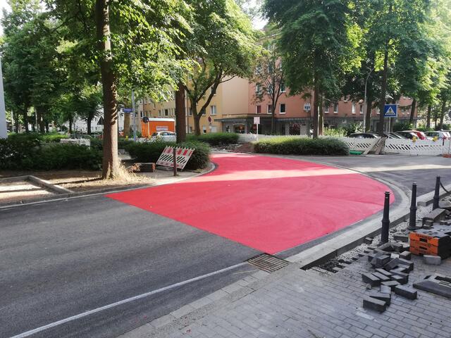 Die mit Rundborden abgesetzte Kurve im Kreuzungsbereich Große Heimstraße und Sonnenplatz glänzt bereits mit kräftiger Rot-Markierung. Die Farbe signalisiert die Vorfahrt für die Verkehrsteilnehmenden auf dem zukünftigen Radschnellweg Ruhr (RS1).
