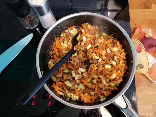 Meine Reihenfolge beim Zugeben ist: Zwiebeln, Knoblauch, Hack, Karotten, Zucchini, Paprika. Wenn alles gar, aber noch bissfest ist, kommen geschälte oder passierte Tomaten drüber.