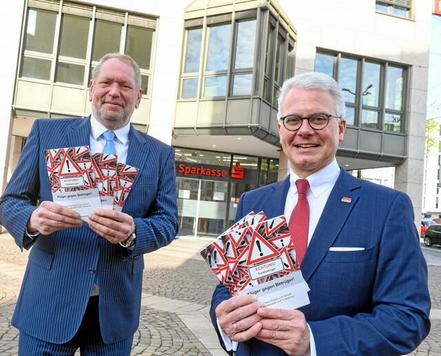 Polizeipräsident Frank Richter und Sparkassenchef Martin Weck mit der Broschüre „Klüger gegen Betrüger“, die in allen Filialen der Sparkasse ausliegt und auf Wunsch auch zugesandt wird.