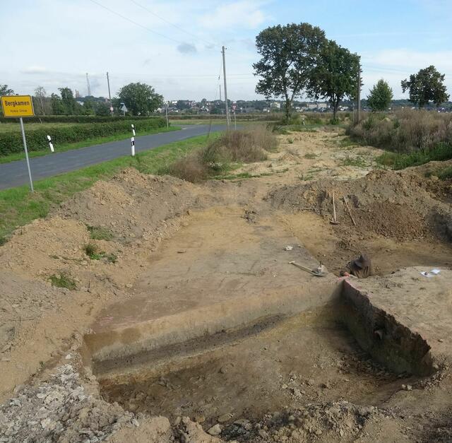 Direkt an der Stadtgrenze von Bergkamen liegt die Untersuchungsfläche, im Vordergrund ist eine Schnitt durch eine besonders große Grube zu sehen, auf deren Sohle eine mit Holzkohle angereicherte Schicht eingelagert ist.
Foto: M. Baales/LWL