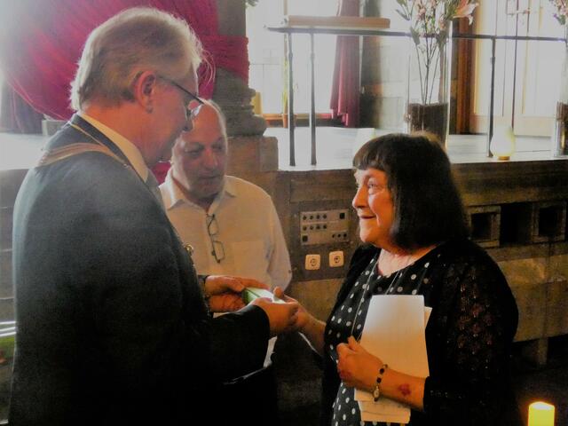 Oberbürgermeister Marc Bucholz überreicht seiner Darlingtoner Amtskollegin Jan Cossins beim Abschiedsdinner im Marmorsaal der Stadthalle ein in der Holzwerkstatt der Mülheimer Fliedner-Werkstätten gefertigtes und mit dem Darlingtoner Stadtwappen signiertes Schreibset als Gastgeschenk. In der Mitte steht der Übersetzer von der Town-Twinning-Association. | Foto: Thomas Emons